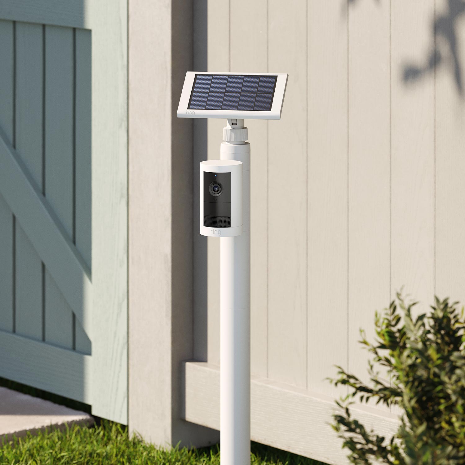Stake Mount (for For Cameras and Solar Panels) - White Stake Mount and adjustable pole with Ring security camera and solar panel installed near a fence outdoors.