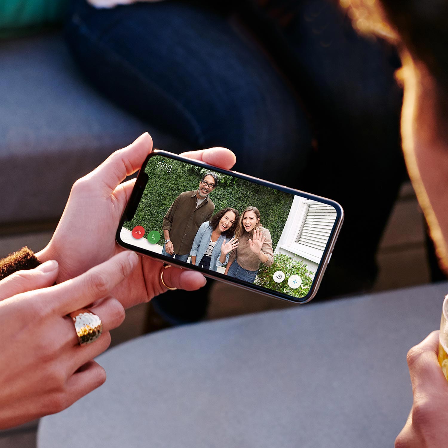 Video Doorbell Wired - Person viewing live Ring Video Doorbell Wired video feed via Ring app of three smiling visitors waving outside.