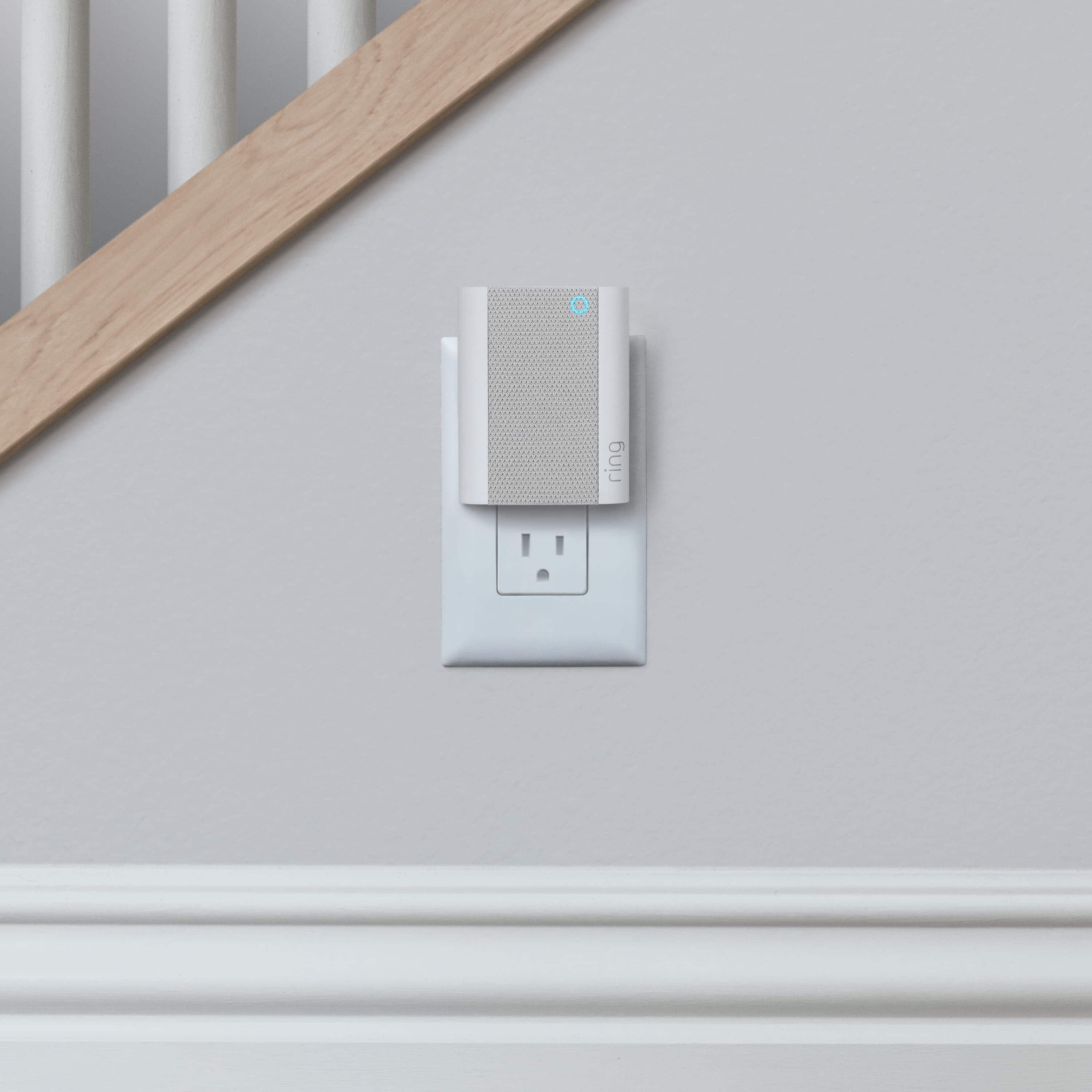 Chime - Ring Chime plugged into wall outlet below staircase, providing customizable audio alerts for Ring doorbells and cameras.