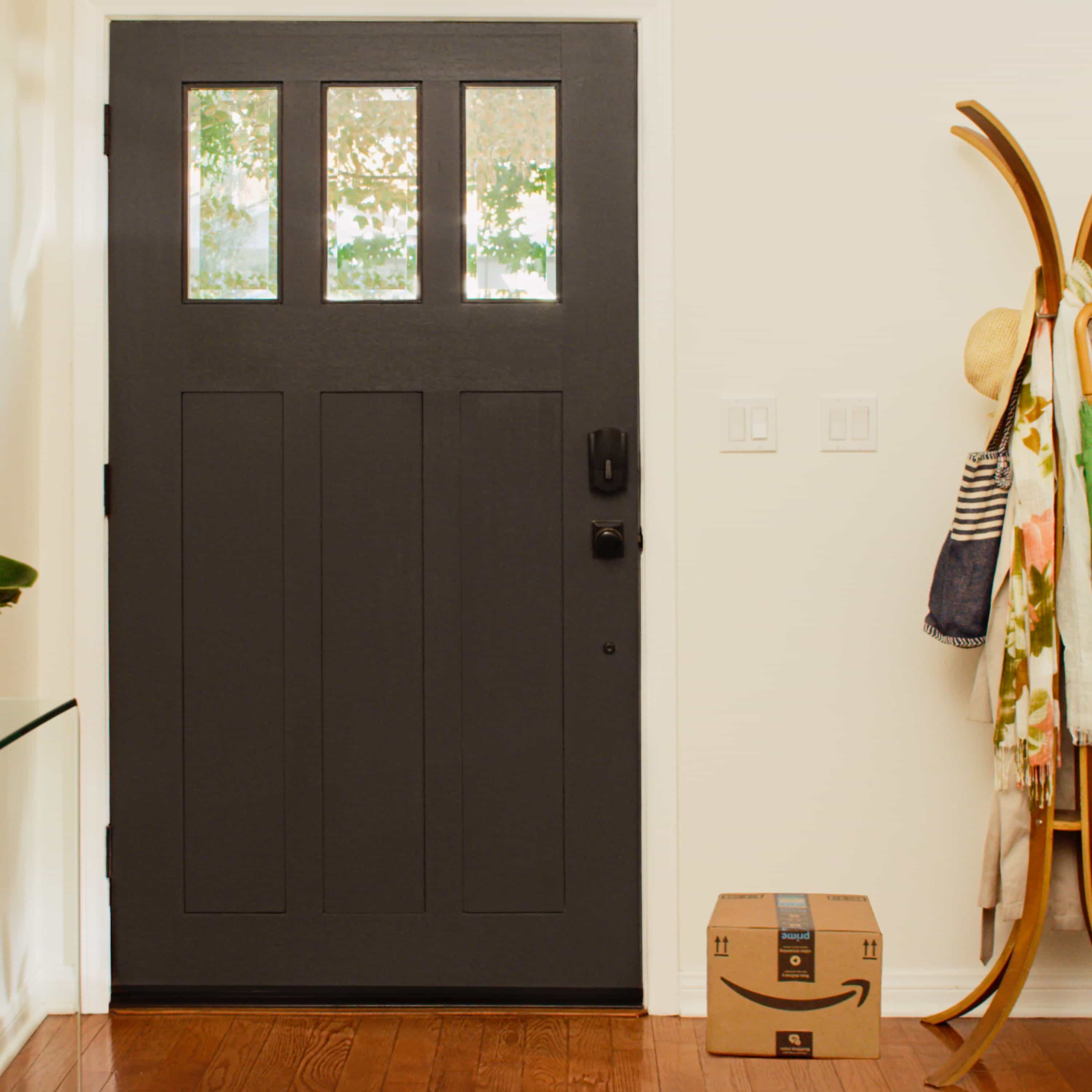 Schlage Encode Smart WiFi Deadbolt with Camelot Trim (for Works with Ring Video Doorbells and Cameras) - Dark front door with Schlage Encode Smart Wi-Fi Deadbolt, shown from inside home with Amazon package on floor.
