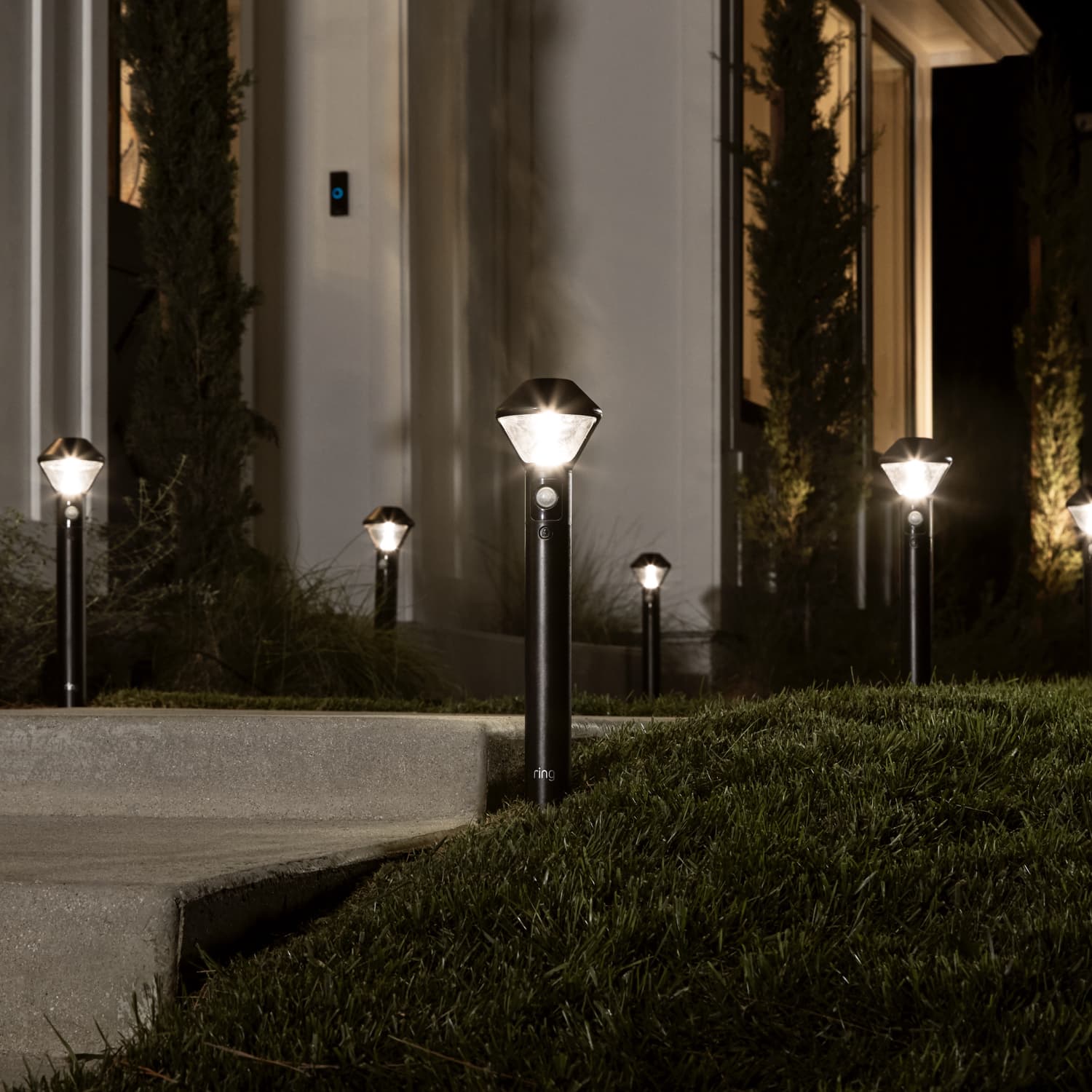 Smart Lighting Solar Pathlight - Multiple solar-powered Ring Pathlights line a walkway and stairs, lighting up automatically when motion is detected.