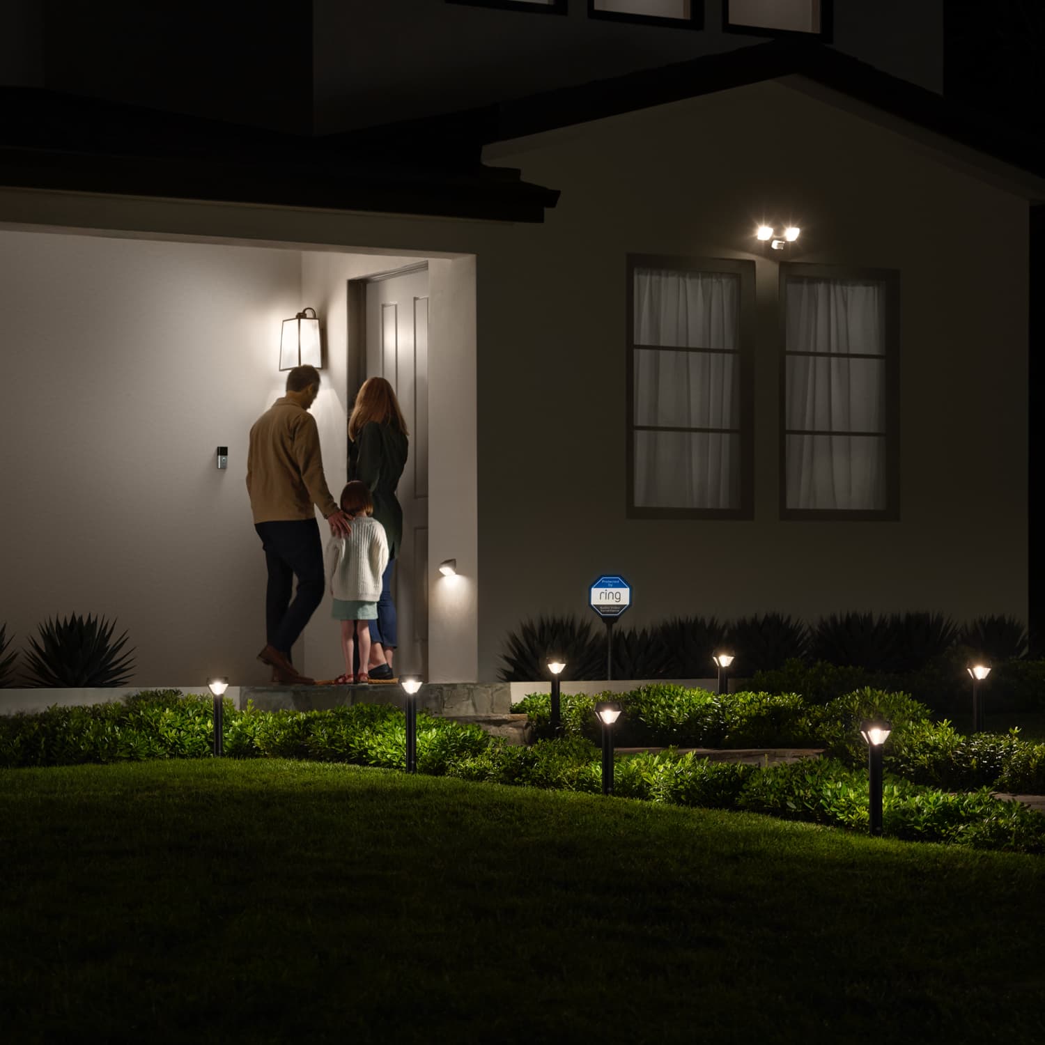 Smart Lighting Solar Pathlight - Family entering a home at night with motion-detecting Ring Solar Pathlights illuminating the walkway automatically.
