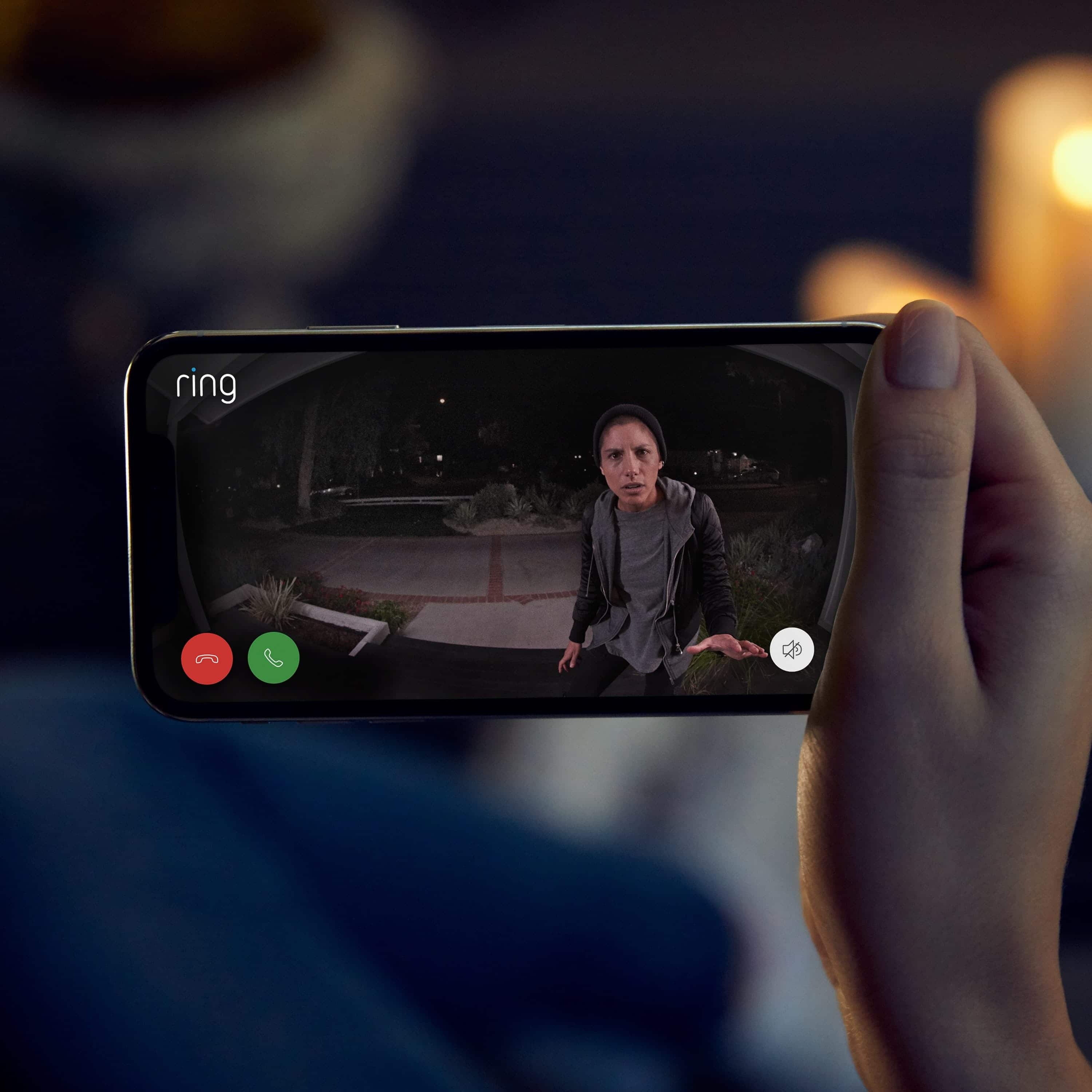 Ring Alarm Outdoor Contact Sensor - Hand holding smartphone showing live Ring video of person on front porch at night, with call and mute buttons visible.