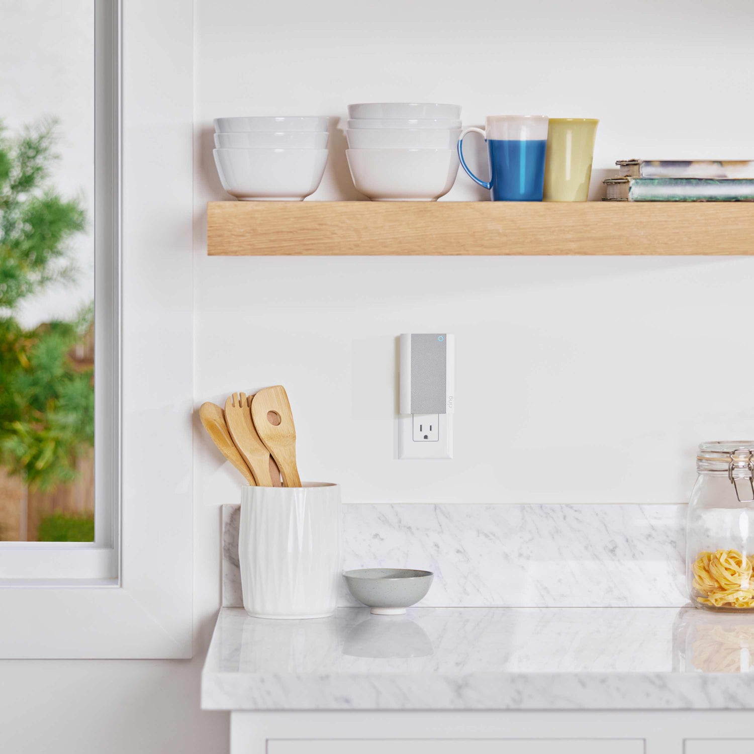 Chime Pro - Ring Chime Pro plugged into kitchen outlet near white bowls, mugs, wooden utensils in a ceramic holder.
