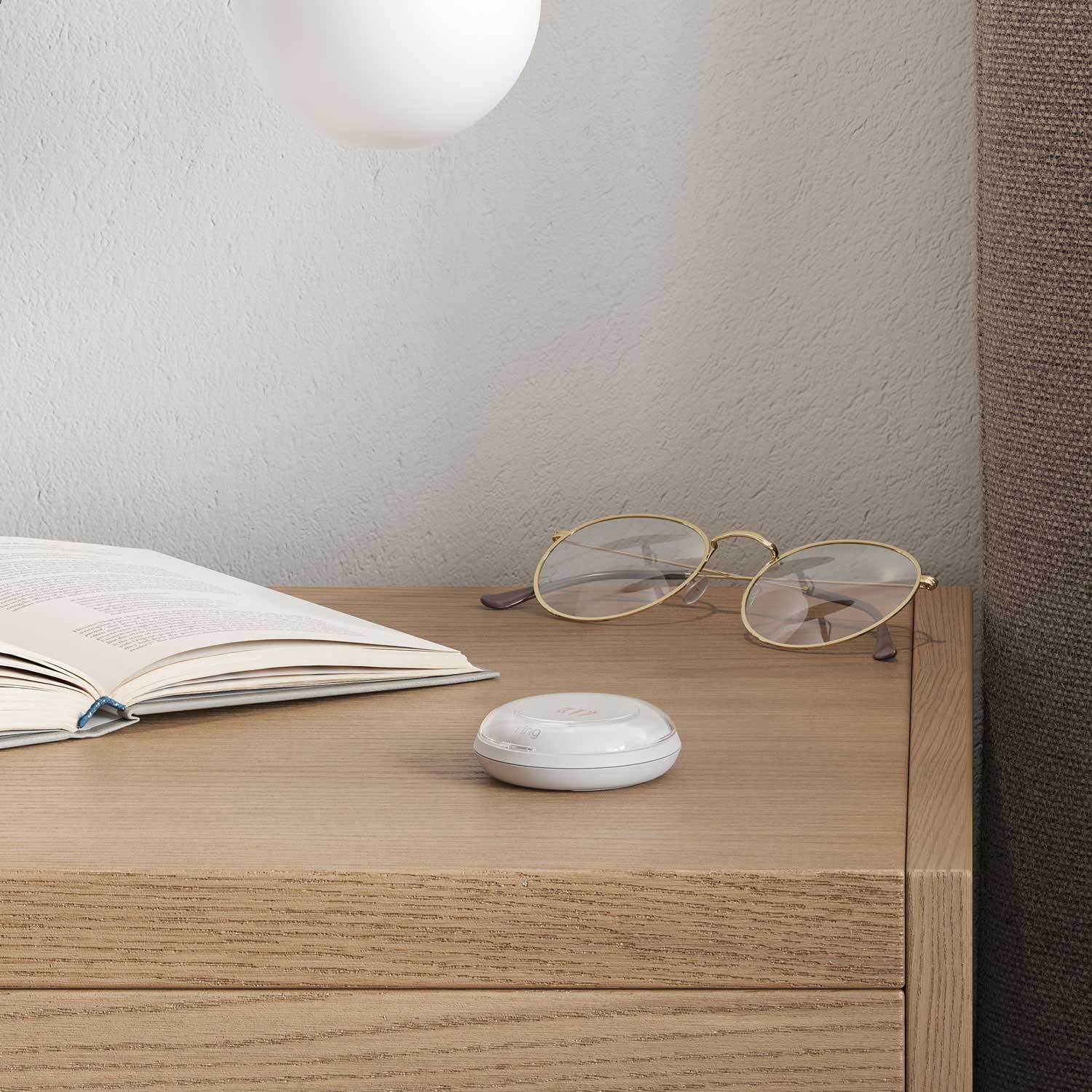 Panic Button (2nd Gen) - White Ring Panic Button 2nd Gen on a bedside table next to open book and glasses.