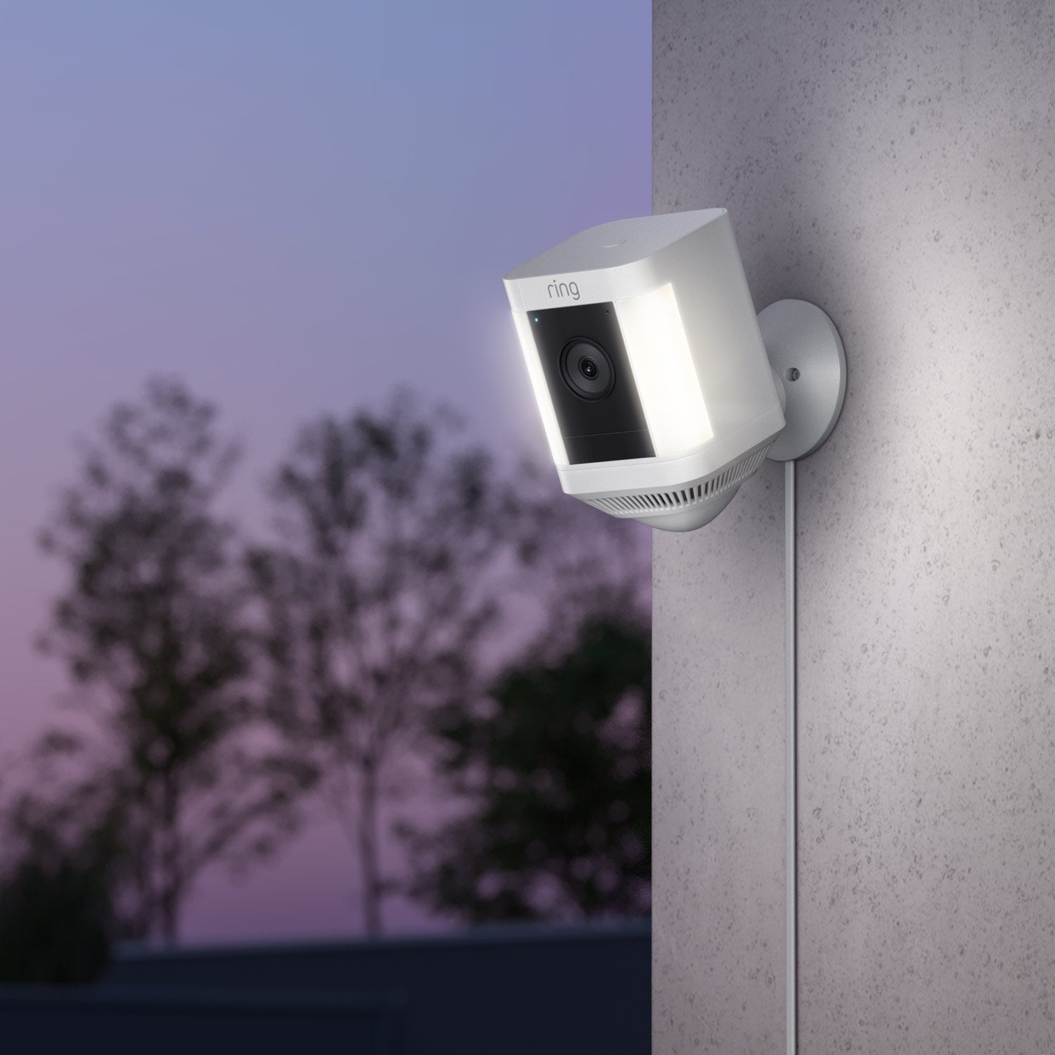 Indoor/Outdoor Power Adapter (USB-C) (for Outdoor Cam Plus, Outdoor Cam Pro, Stick Up Cam Pro, Spotlight Cam Plus, Spotlight Cam Pro)  - Ring Spotlight Cam Plus with illuminated lights mounted on a wall, powered by a USB-C cable, at dusk.