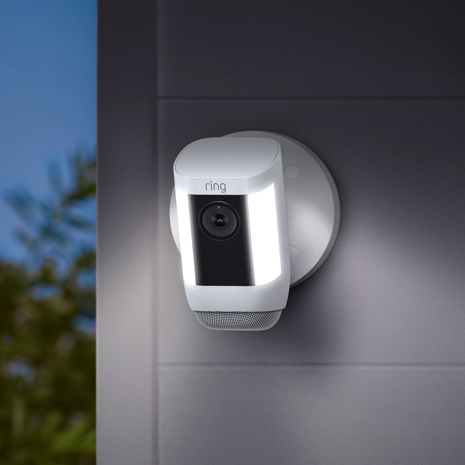 Spotlight Cam Pro (Featuring Retinal 2K) - Wired:White Ring Spotlight Cam Pro with illuminated side lights mounted on an exterior wall at night.