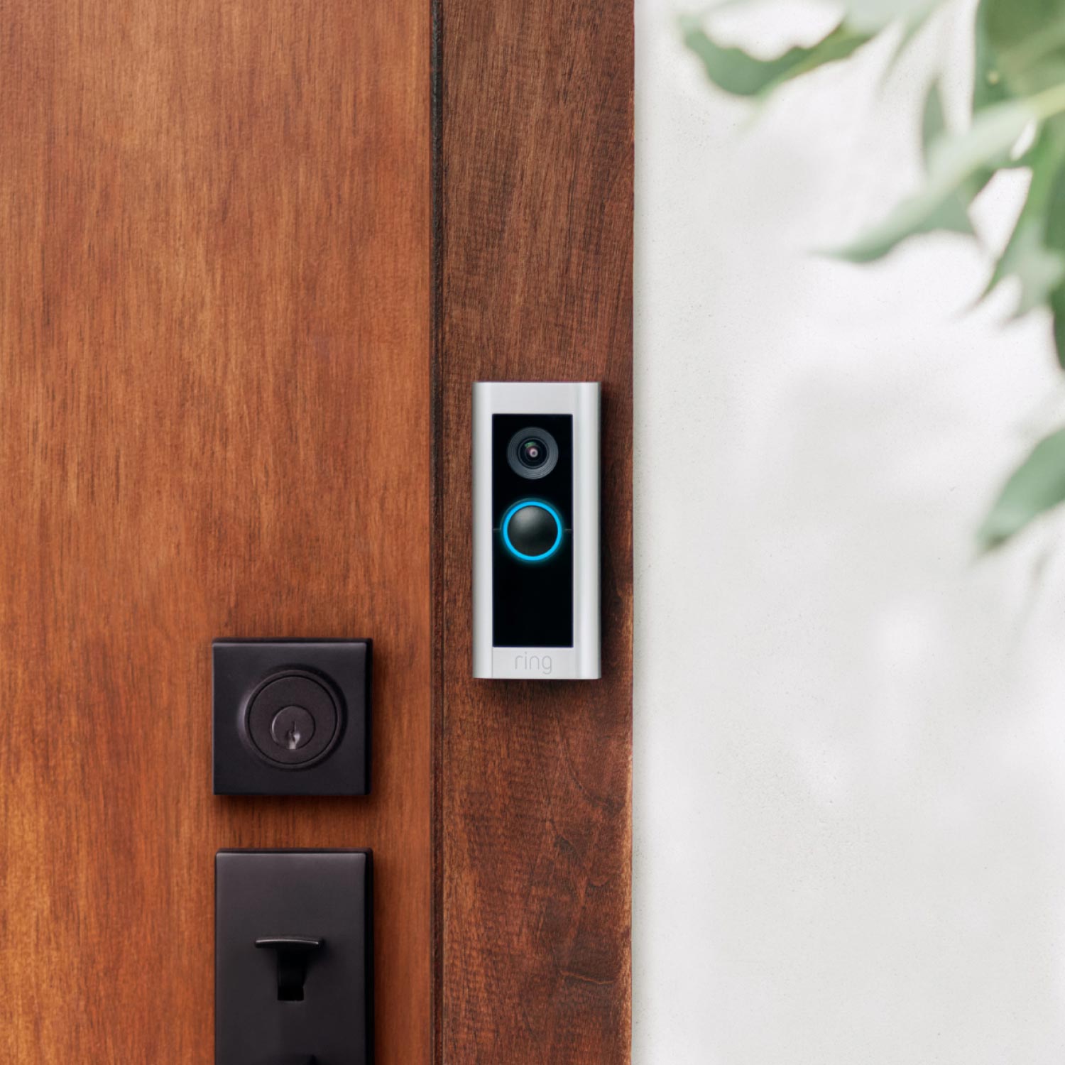 Wired Doorbell Pro (Video Doorbell Pro 2) (Certified Refurbished) - Ring Video Doorbell Pro 2 mounted beside wooden front door, showing camera lens and glowing blue ring button.