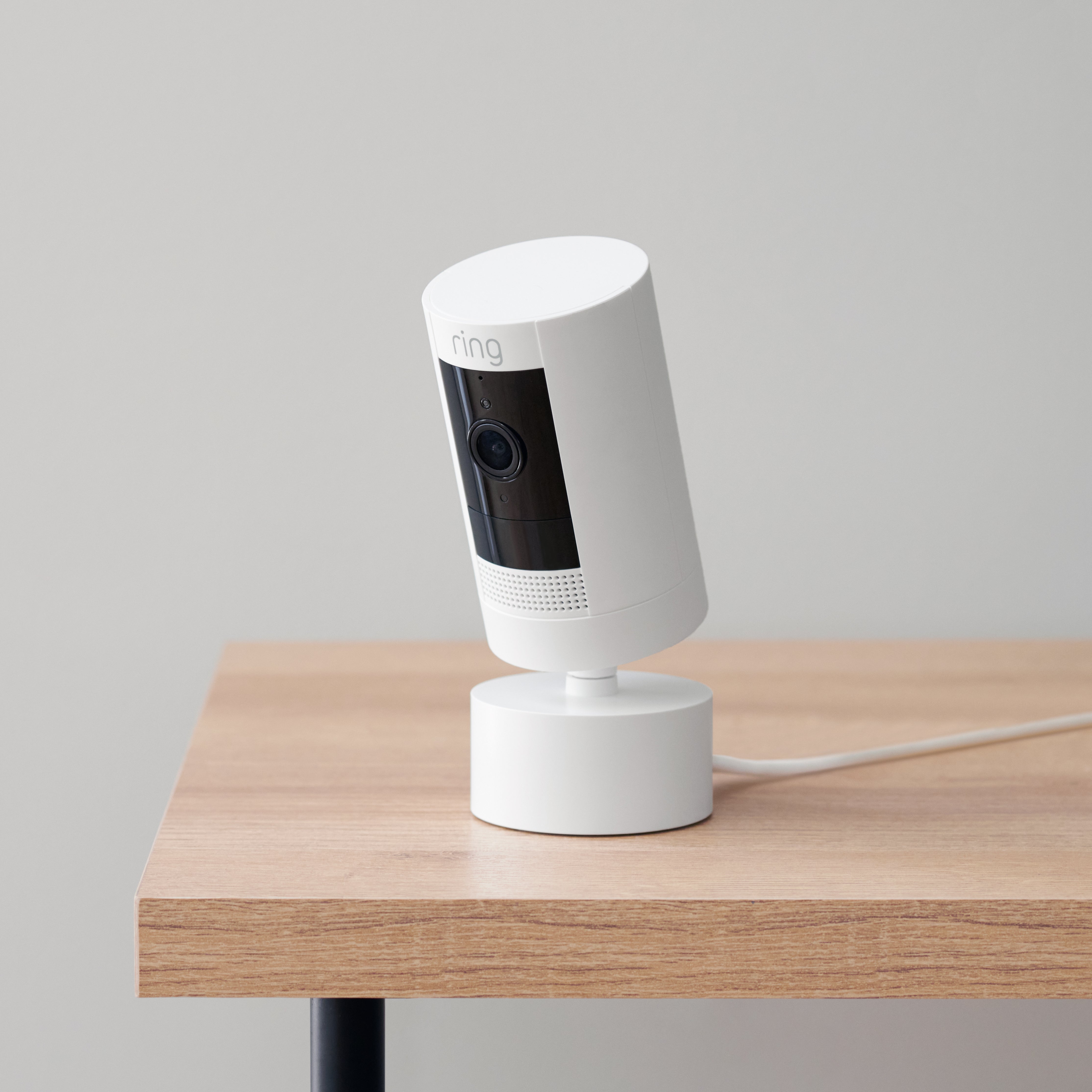 Indoor/Outdoor Pan-Tilt Mount (for Outdoor Cam (Stick Up Cam) Plug-In, 3rd Gen) - White Ring Indoor/Outdoor Pan-Tilt Mount with attached Stick Up Cam on a wood table.