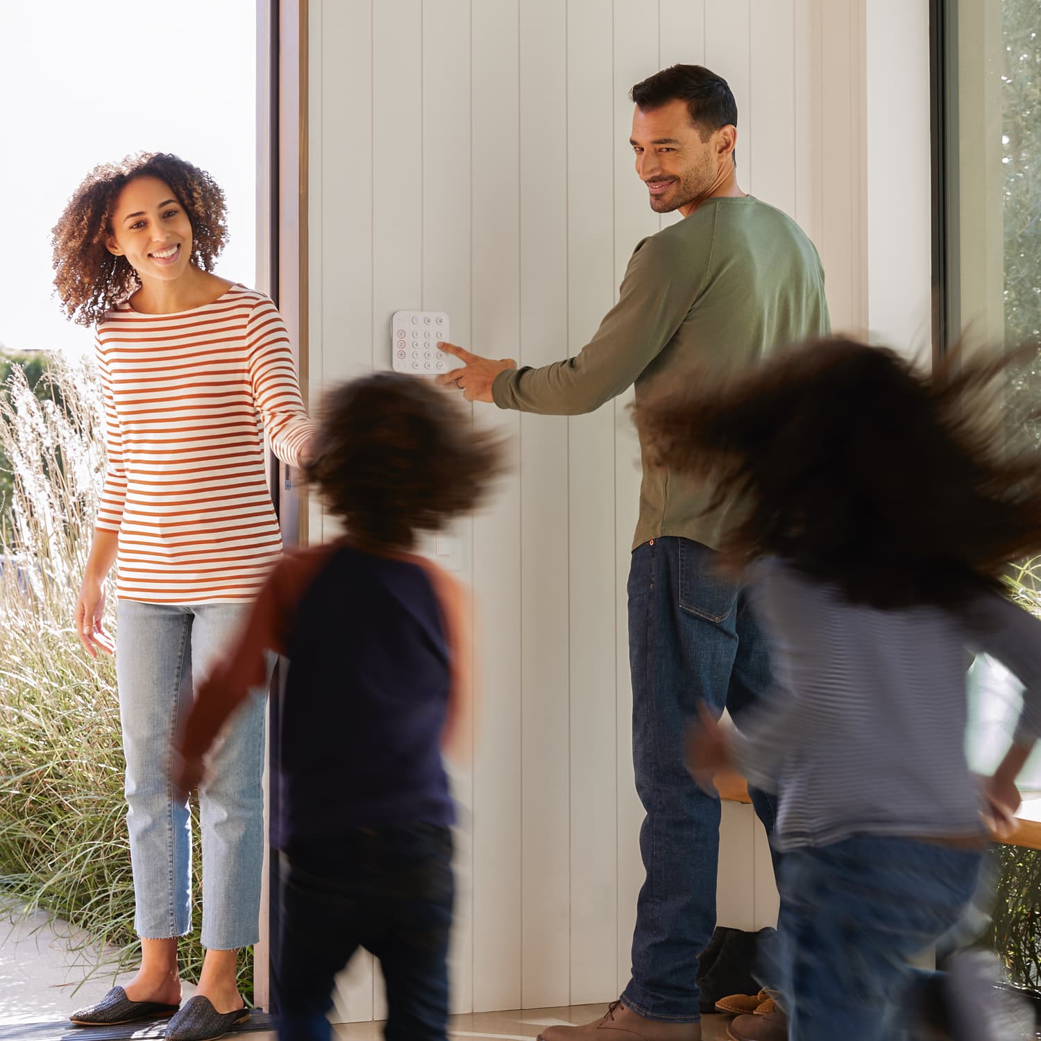 Alarm Security Kit, 8-Piece (Certified Refurbished) - Family exiting home as man uses a Ring Alarm Keypad on the wall, with two kids running toward a woman in doorway.