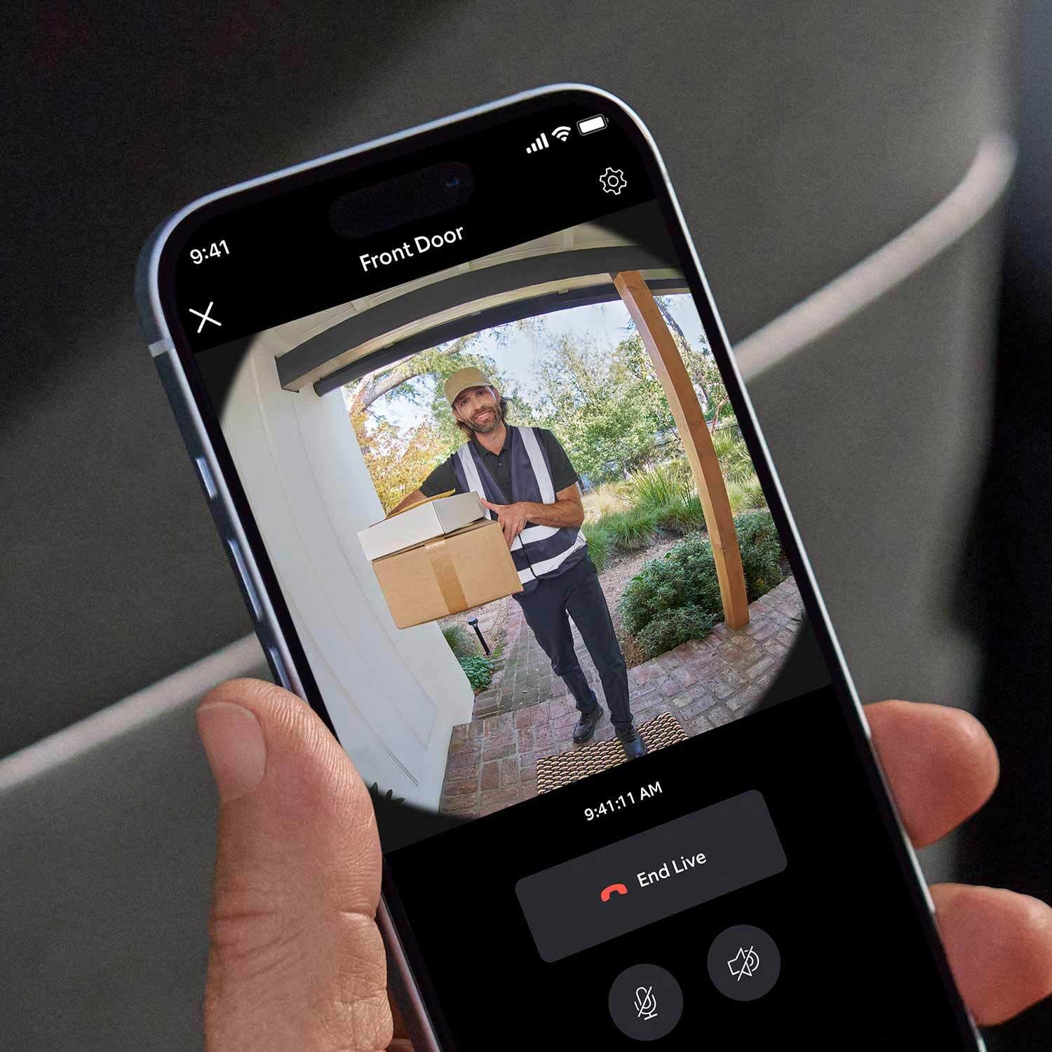 Battery Doorbell + Indoor Cam - Hand holding a smartphone showing live Ring Battery Doorbell video of delivery person with packages at front door.