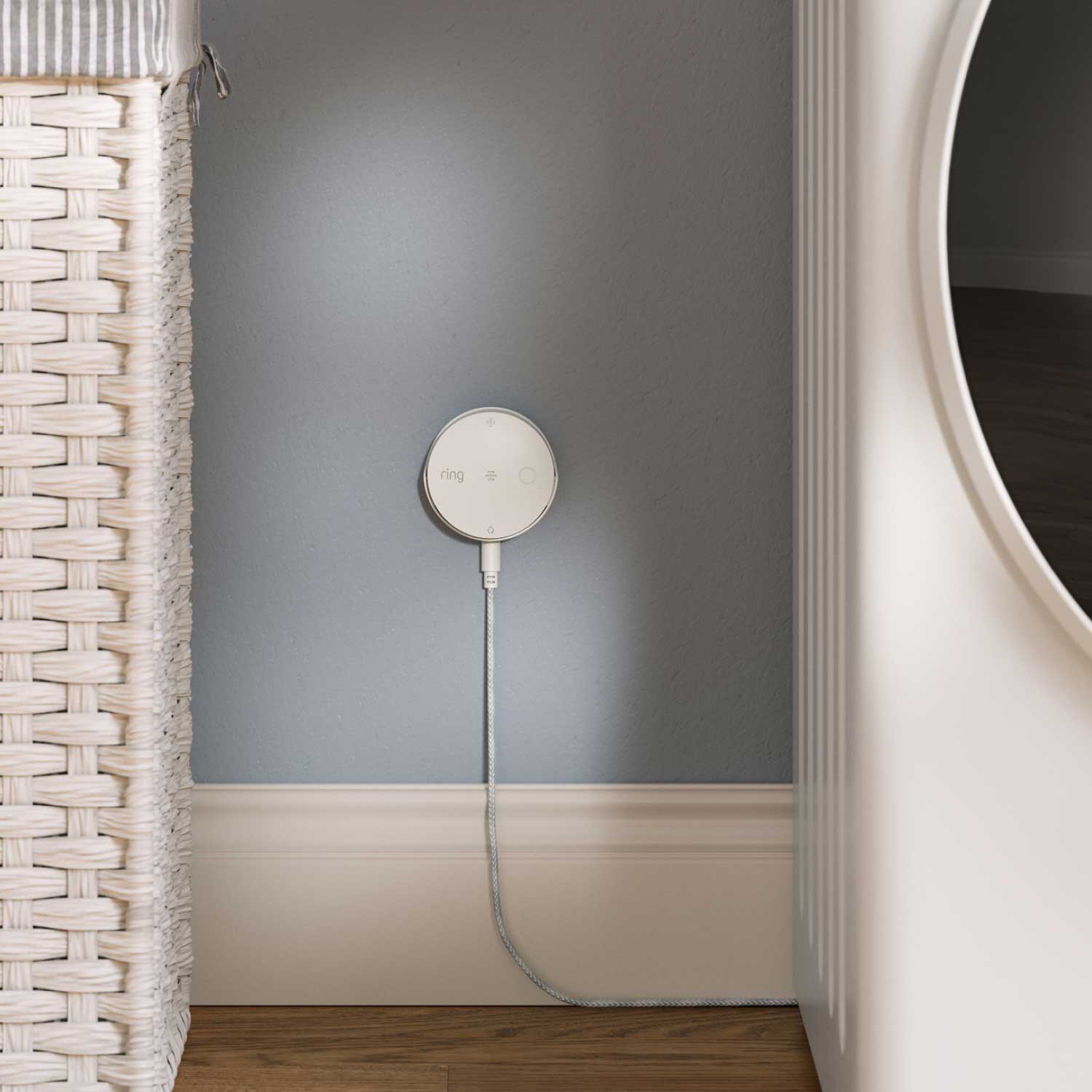 Sump Pump Monitor (Ring Sensors) - Ring sump pump monitor mounted on light blue wall with white trim, next to wicker laundry basket and white washing machine.