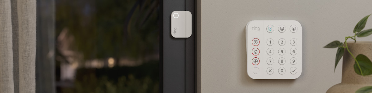 A white Ring Alarm Base Station and Contact Sensor mounted on a wall and door frame