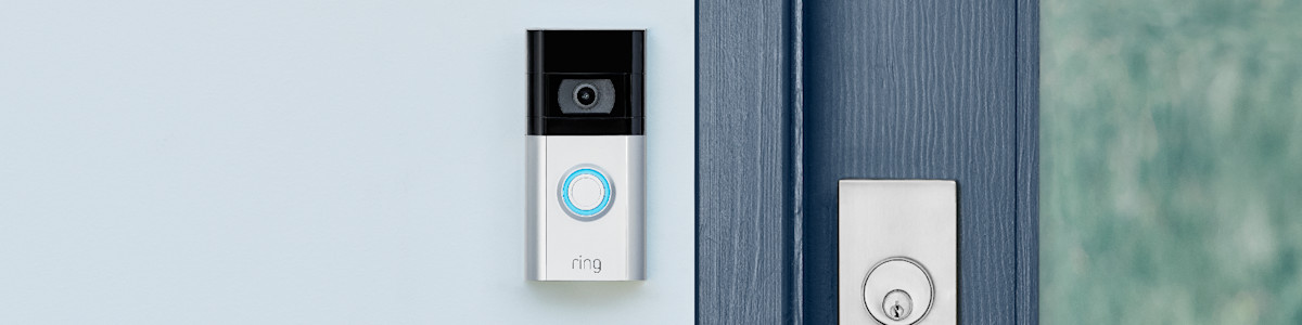 Ring Video Doorbell mounted on white door frame with blue illuminated button