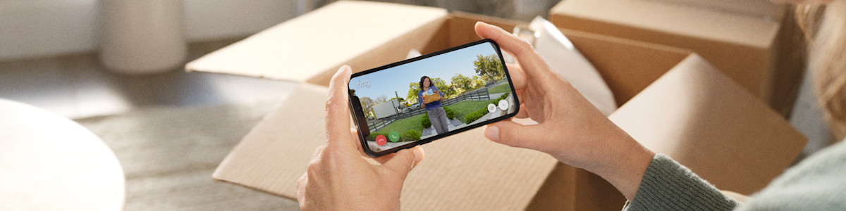 Hands holding phone displaying video call with delivery person at doorstep