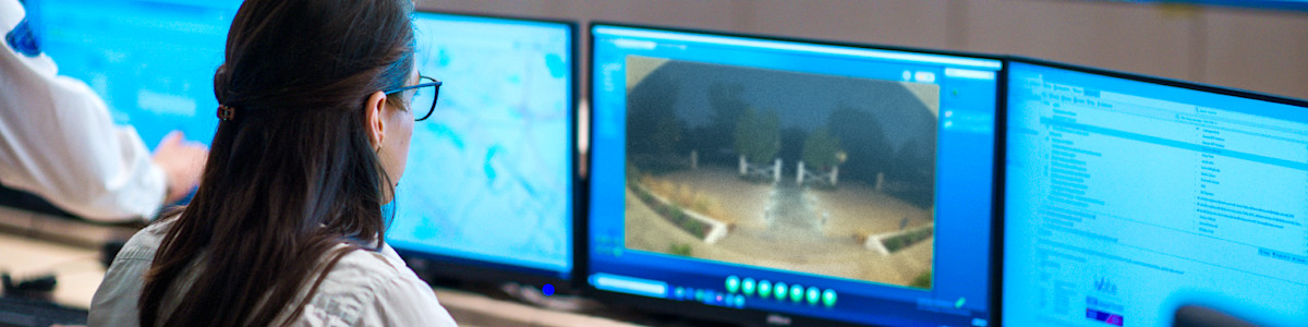 Professional working at desk with multiple computer monitors displaying blue screens