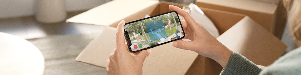 Hands holding a smartphone displaying a backyard scene